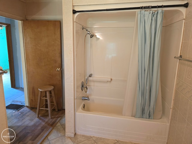 bathroom featuring hardwood / wood-style flooring, shower / bath combo with shower curtain, and tile walls