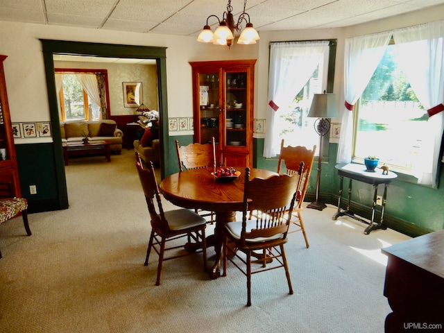 dining area featuring light carpet, an inviting chandelier, and a paneled ceiling