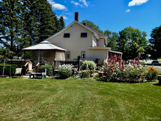 back of property featuring a lawn and a gazebo