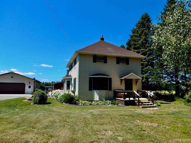 rear view of house featuring a wooden deck, a garage, and a yard