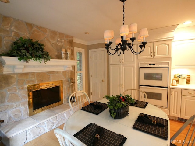 kitchen with white double oven, an inviting chandelier, hanging light fixtures, light wood-type flooring, and ornamental molding