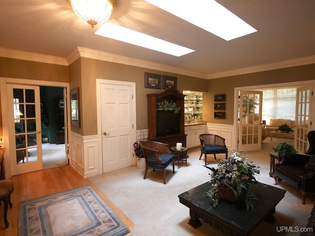 living room with light carpet, french doors, a skylight, and crown molding