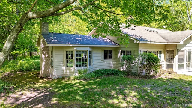 back of property featuring a sunroom and a lawn