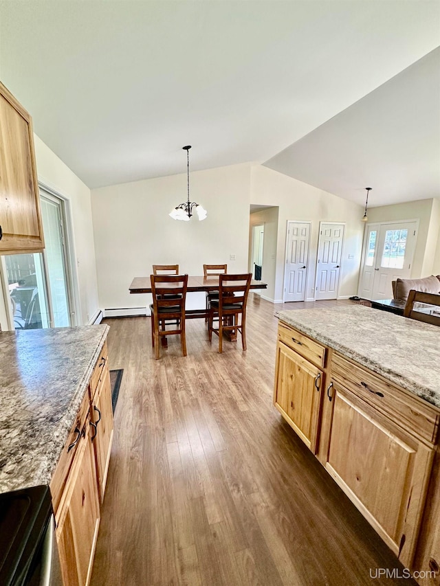 kitchen featuring light stone counters, vaulted ceiling, decorative light fixtures, and dark wood-type flooring