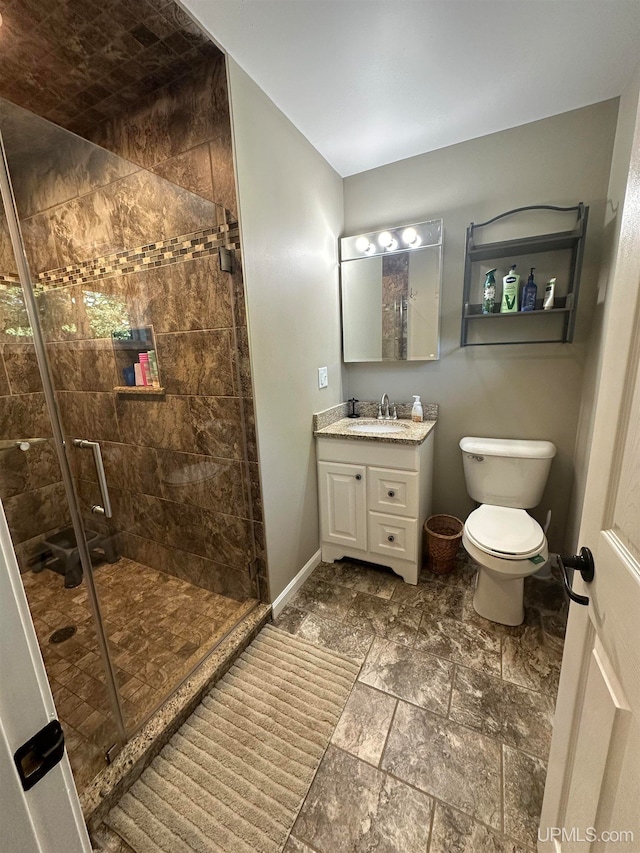 bathroom featuring a shower with door, vanity, and toilet