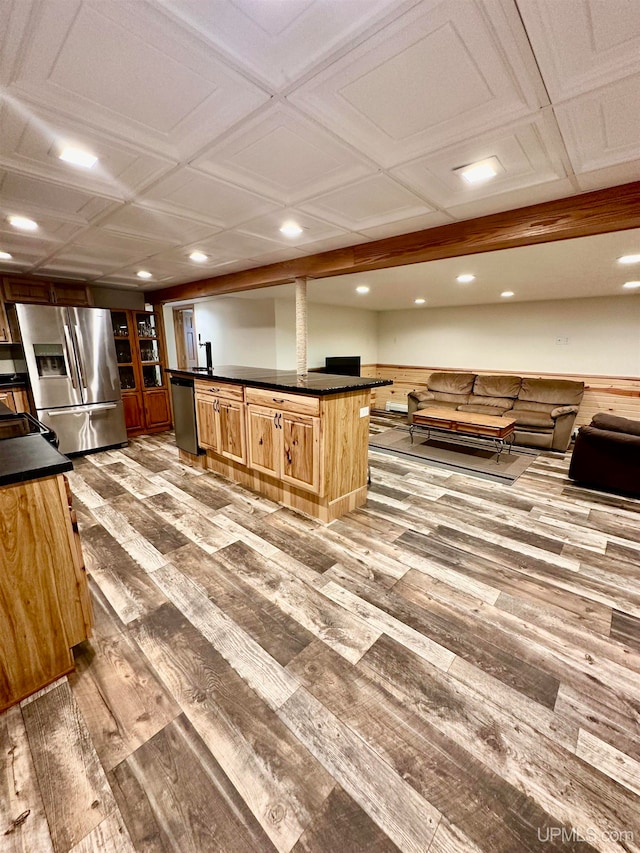 kitchen with wood-type flooring, a center island, coffered ceiling, a kitchen breakfast bar, and stainless steel appliances