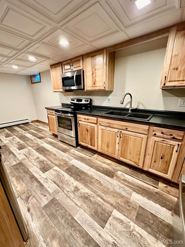 kitchen featuring stainless steel appliances, light wood-type flooring, sink, and a baseboard heating unit