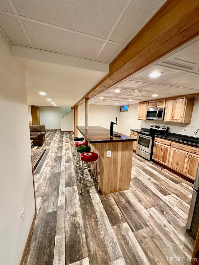 kitchen featuring sink, a kitchen island, stainless steel appliances, a breakfast bar area, and light wood-type flooring