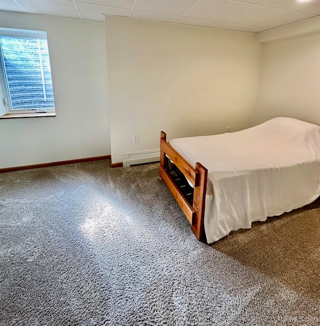 carpeted bedroom with a baseboard radiator and a drop ceiling