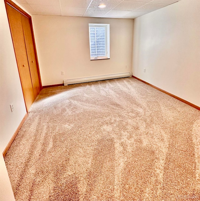 spare room featuring light colored carpet, baseboard heating, and a paneled ceiling