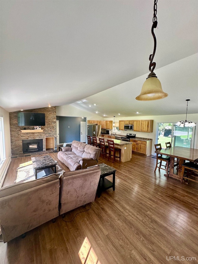 living room with a stone fireplace, vaulted ceiling, and hardwood / wood-style flooring