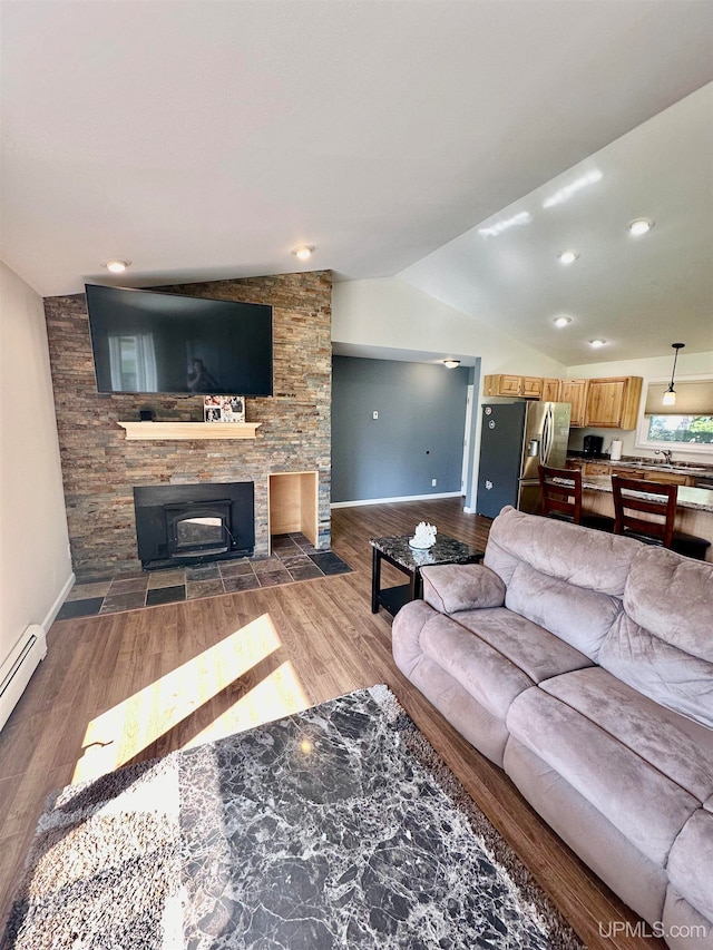 living room with a fireplace, vaulted ceiling, a baseboard heating unit, and dark wood-type flooring