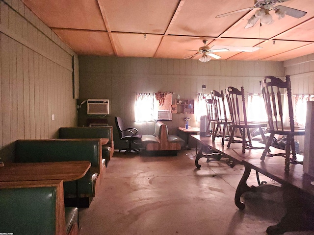 misc room featuring wooden walls, concrete flooring, ceiling fan, and a wall mounted AC