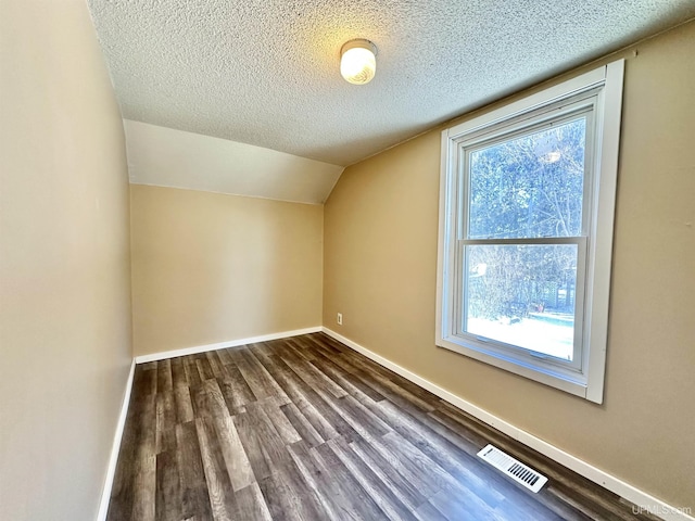 additional living space with a healthy amount of sunlight, dark wood-type flooring, and a textured ceiling