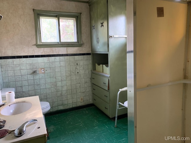 bathroom featuring tile walls, toilet, and sink