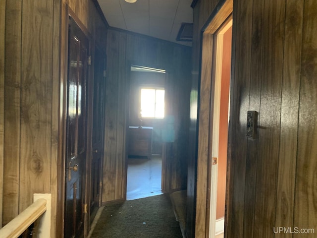 hall featuring wooden walls and carpet flooring