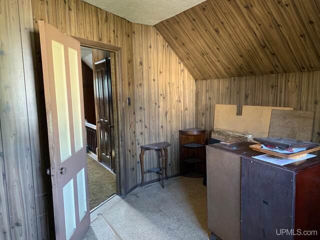 interior space featuring wooden walls, vaulted ceiling, and light carpet