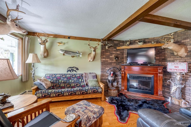 living room with wood-type flooring, a textured ceiling, beamed ceiling, a large fireplace, and brick wall