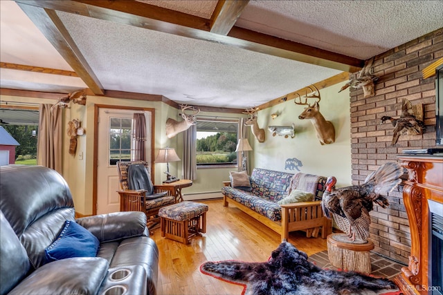 living room featuring beamed ceiling, a brick fireplace, a textured ceiling, hardwood / wood-style flooring, and a baseboard radiator