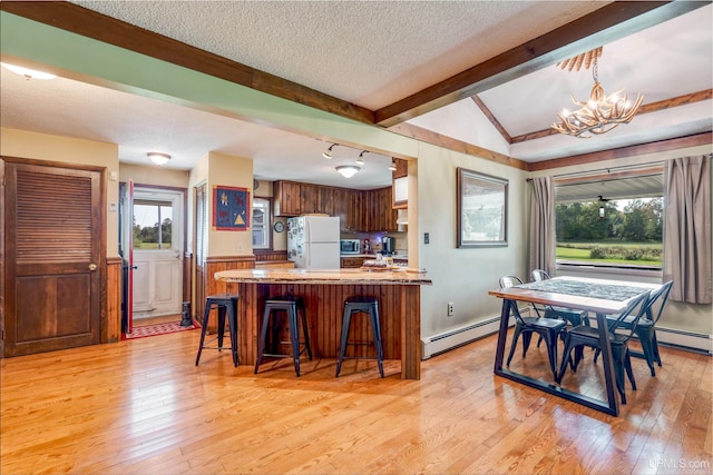 dining area featuring a notable chandelier, vaulted ceiling with beams, light hardwood / wood-style floors, and a healthy amount of sunlight