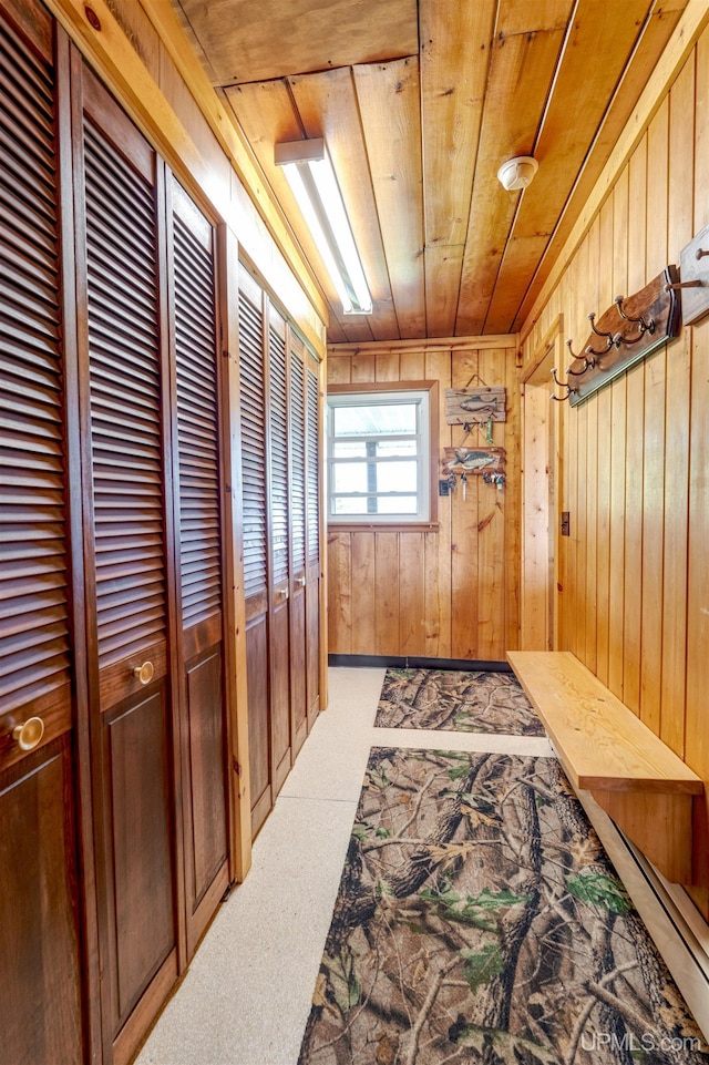 hallway with light colored carpet, wood walls, and wooden ceiling