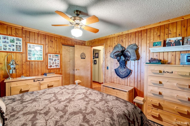 bedroom with ceiling fan, a textured ceiling, and wooden walls