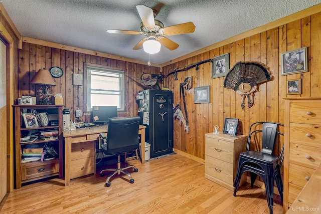 office with light hardwood / wood-style floors, ceiling fan, wood walls, and a textured ceiling