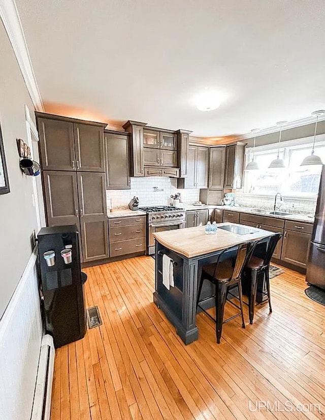 kitchen with pendant lighting, a kitchen bar, light hardwood / wood-style flooring, appliances with stainless steel finishes, and crown molding