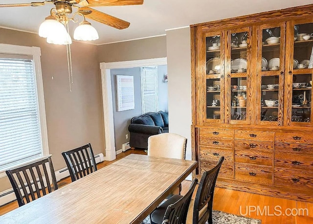 dining area featuring ceiling fan, light hardwood / wood-style flooring, crown molding, and baseboard heating