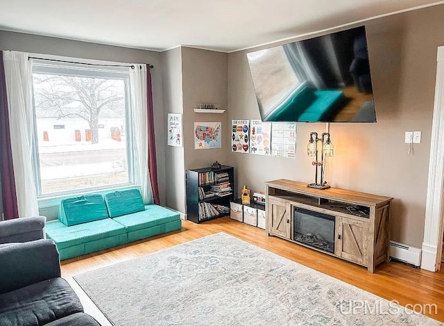 living room with baseboard heating and light hardwood / wood-style floors