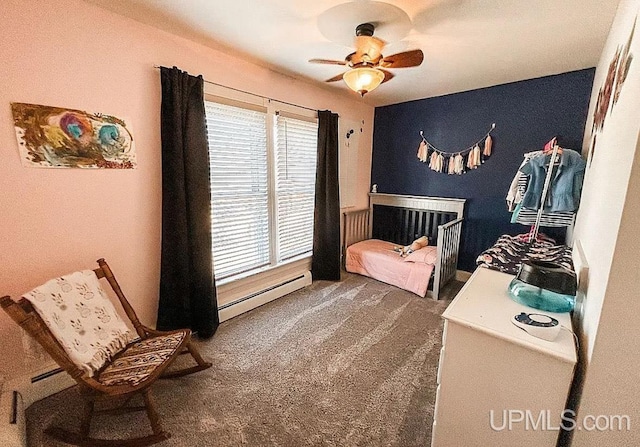 bedroom featuring dark carpet, a baseboard heating unit, ceiling fan, and a nursery area