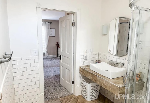 bathroom featuring tile walls, a shower, and sink