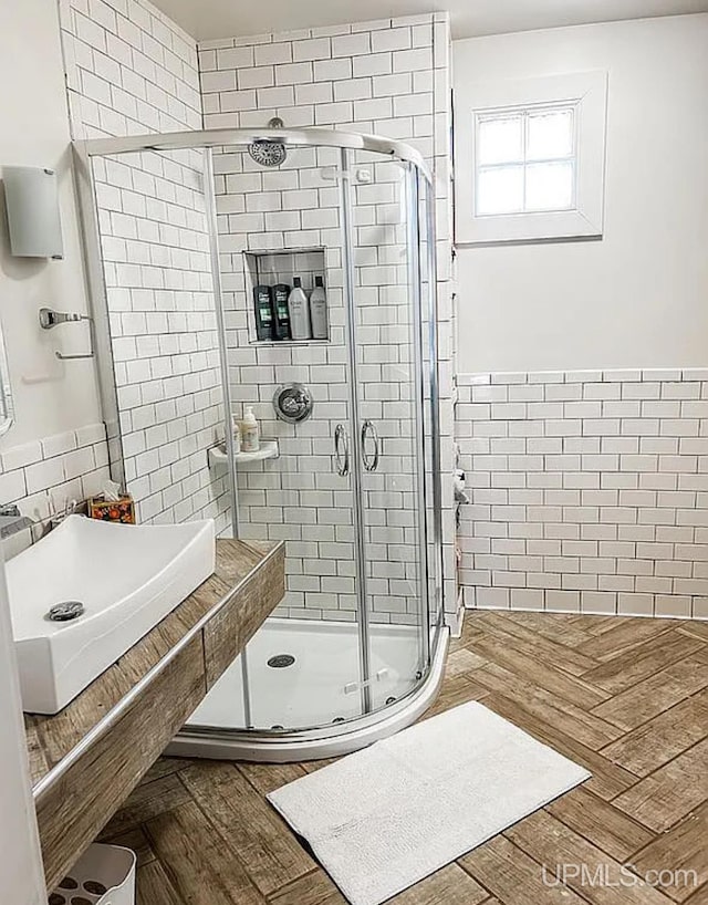 bathroom featuring tile walls, walk in shower, hardwood / wood-style floors, and sink