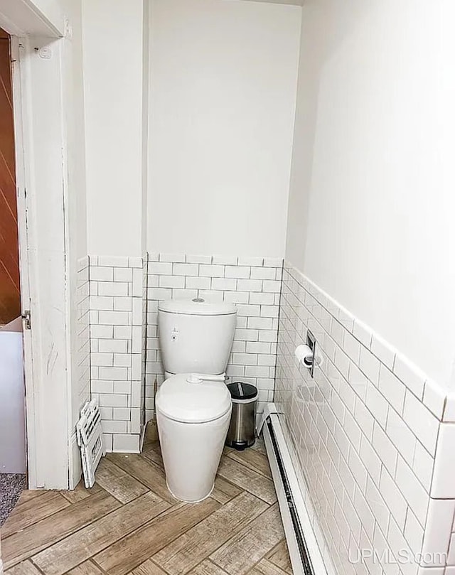 bathroom with wood-type flooring, a baseboard radiator, tile walls, and toilet