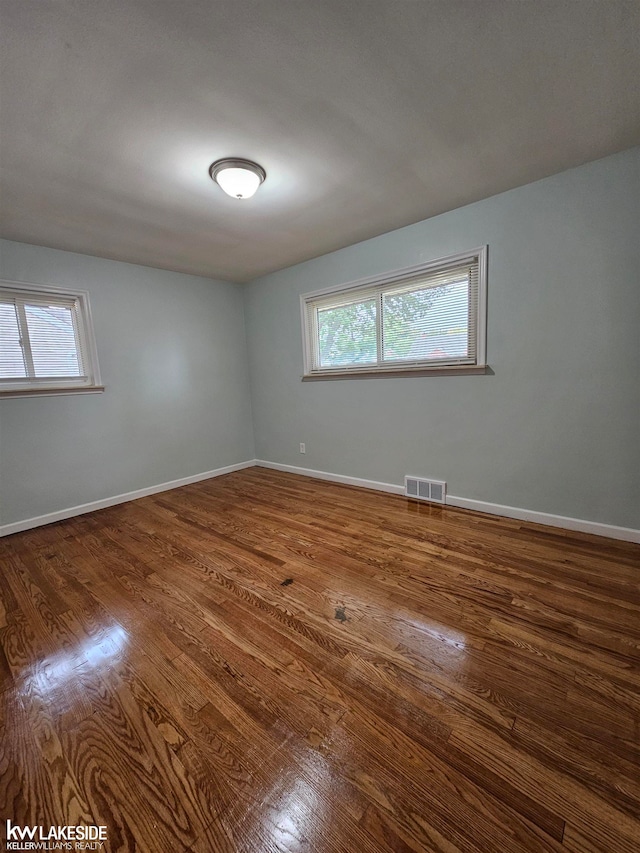 spare room with a healthy amount of sunlight and hardwood / wood-style floors