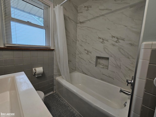 bathroom with tile walls, toilet, shower / bathtub combination with curtain, and tile patterned floors