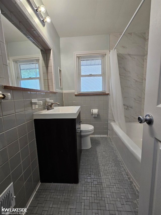 full bathroom featuring tile walls, vanity, a wealth of natural light, shower / tub combo with curtain, and toilet