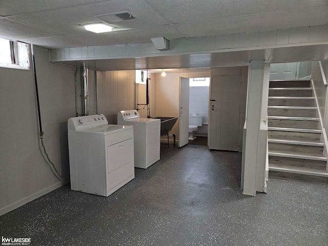 basement featuring sink, a drop ceiling, independent washer and dryer, and a healthy amount of sunlight