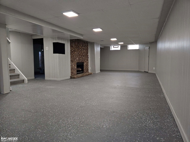 basement with a paneled ceiling and a large fireplace