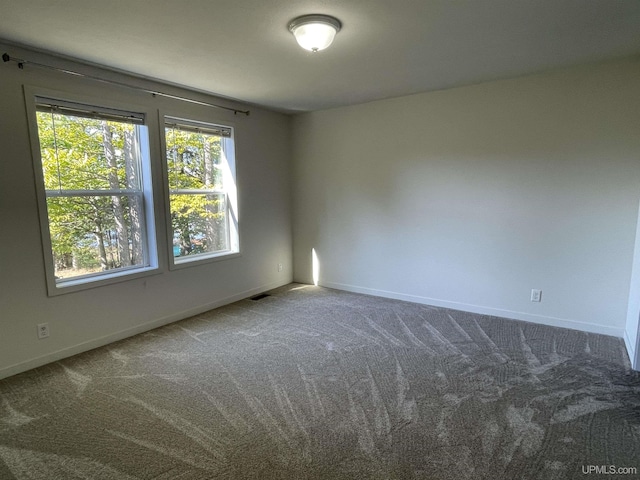 empty room featuring carpet, visible vents, and baseboards