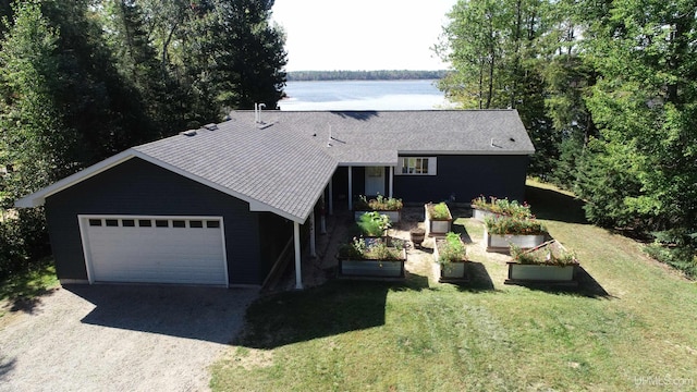 view of front of house featuring a front yard, a shingled roof, a vegetable garden, a garage, and driveway