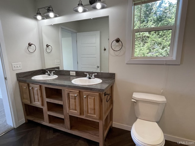 full bath with double vanity, baseboards, a sink, and toilet