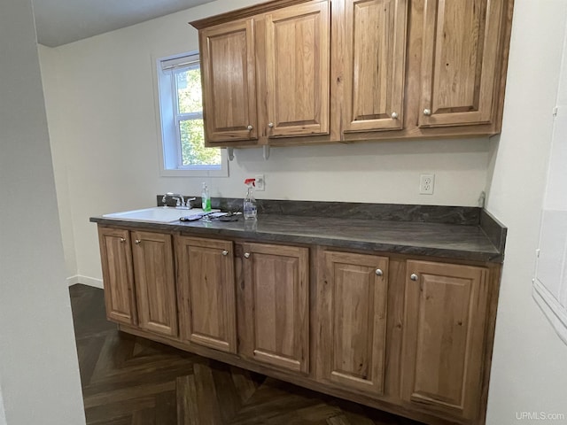 kitchen featuring a sink, dark countertops, and brown cabinets