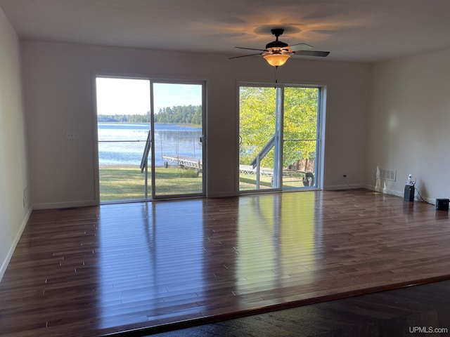 spare room with ceiling fan, baseboards, dark wood finished floors, and visible vents