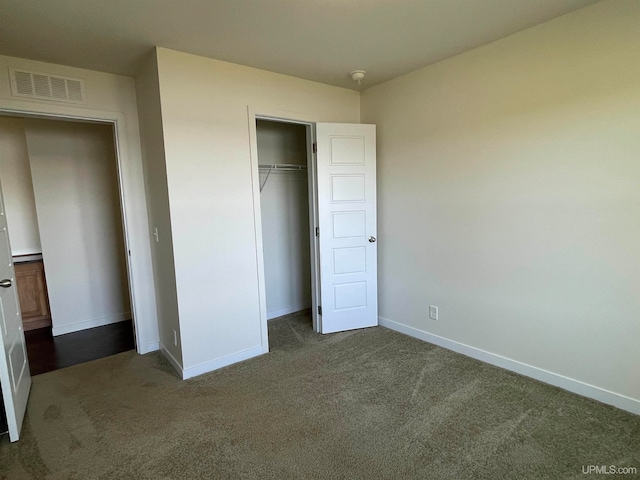 unfurnished bedroom with dark carpet and a closet