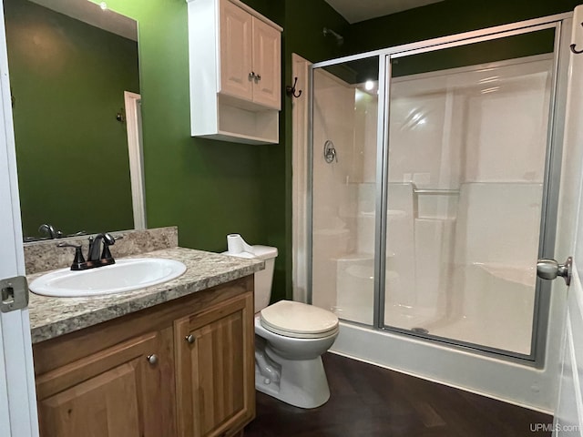 bathroom with hardwood / wood-style floors, vanity, toilet, and an enclosed shower