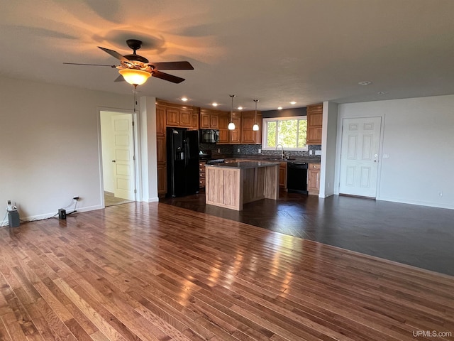 kitchen with black appliances, a kitchen island, dark wood-type flooring, and ceiling fan