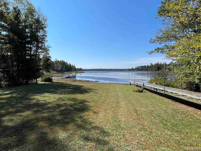 view of dock with a lawn and a water view