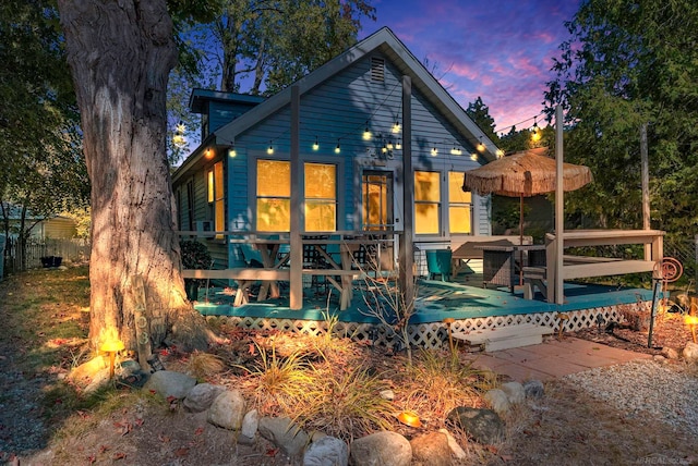 back house at dusk featuring a deck