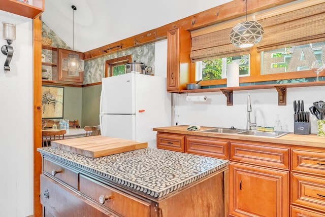 kitchen with lofted ceiling, sink, white refrigerator, and decorative light fixtures